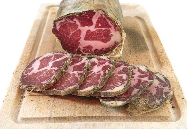 Sliced cured meat on a wooden board, showcasing marbled patterns and a rustic, artisanal feel. The tones are rich and earthy.