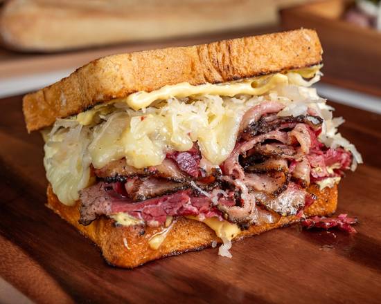 Deli sandwich with meat and sauerkraut on a wooden cutting board