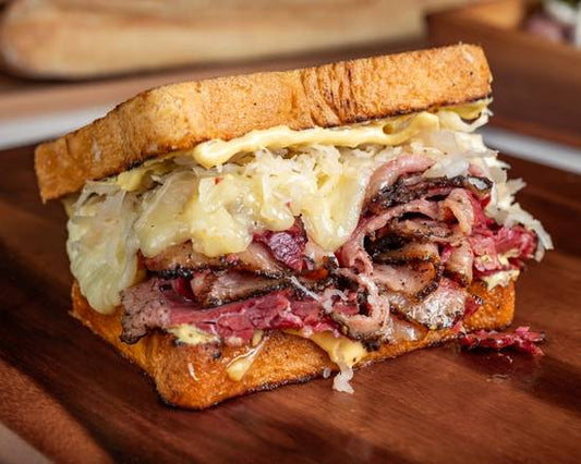 Deli sandwich with meat and sauerkraut on a wooden cutting board