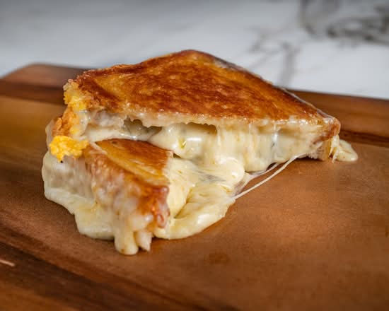 Grilled cheese sandwich on a wooden cutting board with a marble background