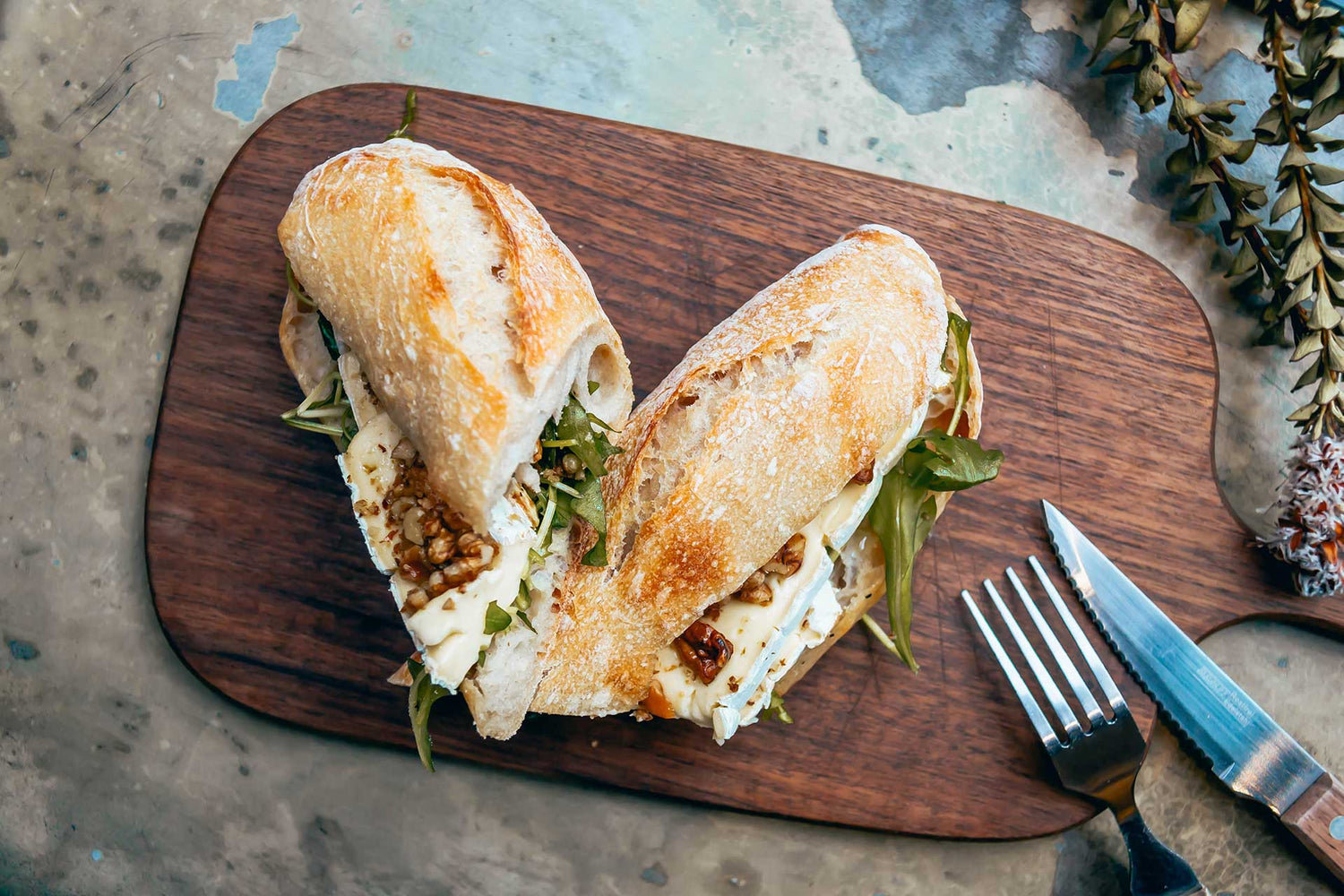 A sandwich on top of a wooden cutting board.
